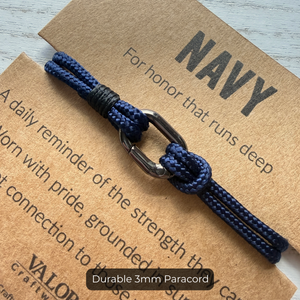 Navy paracord bracelet on a brown card with text
