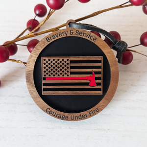 Wooden ornament with American flag design and engraved text on a white background with red berries.