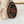 Wooden pendant with American flag design and engraved text, leaning against a tree trunk.