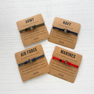 Four bracelets with different colored bands on cards labeled 'Army', 'Navy', 'Air Force', and 'Marines' on a textured white background.