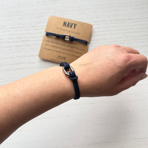 Navy blue bracelet on a wrist with a matching card labeled 'NAVY' on a light background