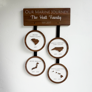 Wooden wall hanging with engraved locations and years, personalized for a family.