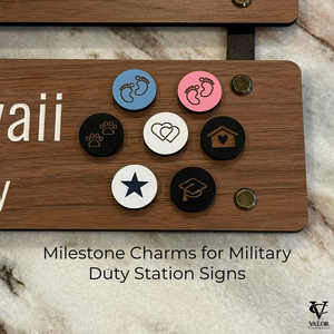Wooden sign with milestone charms for military duty station signs on a marble surface.