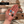 Hand holding milestone charms with a blurred background of journey sign.