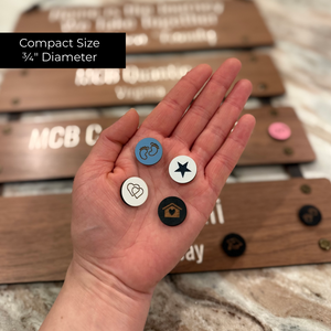 Hand holding milestone charms with a blurred background of journey sign.
