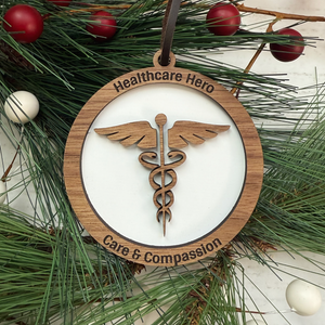 Decorative ornament with 'Healthcare Hero' and 'Care & Compassion' text on a wooden circle, surrounded by greenery and berries.
