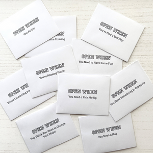 Set of white envelopes with black text on a light wooden surface