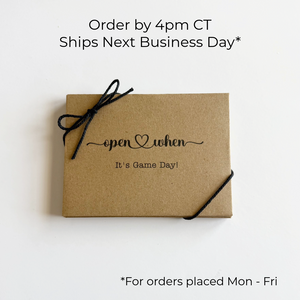 Kraft paper box with 'open when it's Game Day!' text and black ribbon on a white background.
