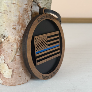 Wooden ornament with American flag design and text 'Honor & Duty', 'Protect & Serve' on a light background.