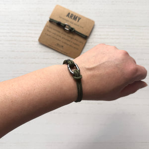 Hand wearing a bracelet with an 'Army' branded card in the background